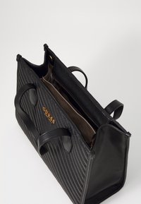 Sac à main noir matelassé en cuir texturé, doté de deux poignées, d'un logo doré et d'un compartiment intérieur zippé.
