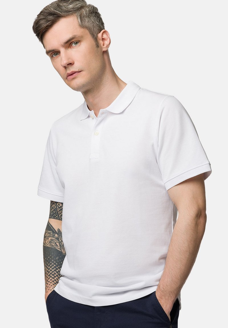 Biała bawełniana koszulka polo z krótkim rękawem, klasycznym kołnierzykiem oraz trzema guzikami; charakteryzuje się subtelną teksturą i dopasowanym krojem.