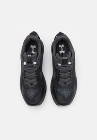 Scarpe sportive nere e grigie con una parte superiore in rete, colletto imbottito e logo a contrasto. Punta arrotondata e suola testurizzata per una migliore aderenza.