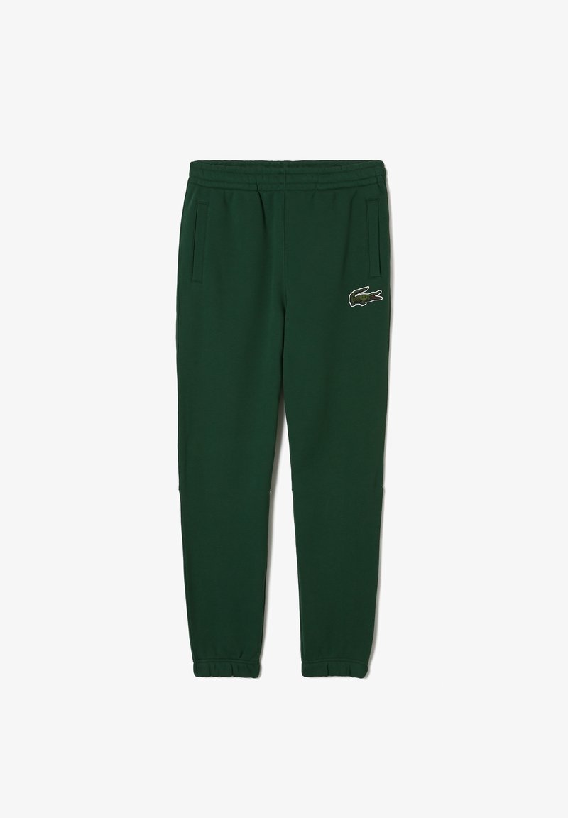 Pantalones jogger de color verde oscuro con cinturilla y puños elásticos, bolsillos laterales y un pequeño logo bordado de un cocodrilo en el muslo derecho.