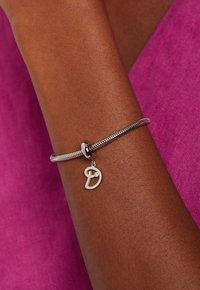 Zilveren armband met een zigzag-kettinkje en een decoratieve letter "D" hanger met een kleine heldere edelsteen.