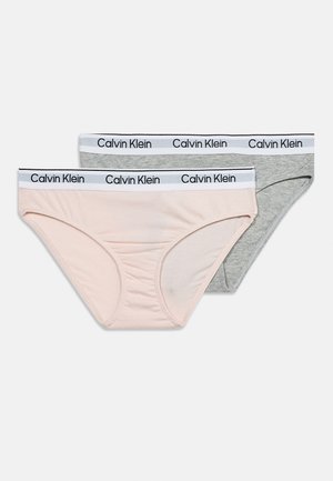 Δύο γυναικεία σλιπ Calvin Klein, ένα ανοιχτό ροζ και ένα γκρι, και τα δύο με λευκή μέση με μαύρο λογότυπο Calvin Klein.