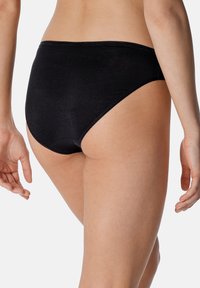 Zwarte bikinionderkant met een geribde textuur, met een hoge taille en eenvoudige stiksels langs de randen. Geen extra versieringen.