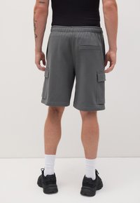 Pantaloni cargo grigi realizzati in tessuto morbido, dotati di una vita elastica, due tasche laterali e una tasca posteriore con pattina.