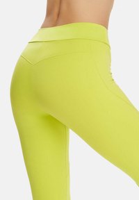 Leggings verde lime fabricate dintr-un material elastic, cu un talie înaltă și cusături conturate în spate pentru a accentua forma.