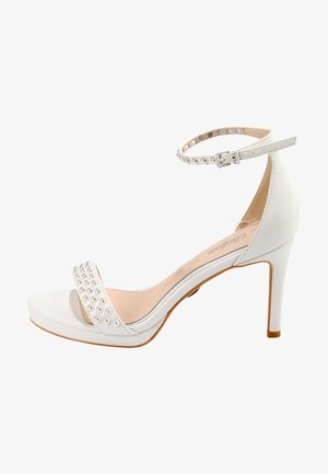 Sandale à talon haut blanche avec une sangle de cheville, ornée d'un accent en perles sur le devant et d'une finition lisse et brillante. Talon aiguille fin.