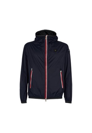Veste en nylon bleu marine avec un devant zippé, des bandes d'accent rouge et blanc, des poignets élastiques et une capuche. Dispose de deux poches latérales zippées.