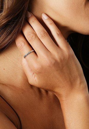 Silberner Bandring mit Kettenglied-Design und poliertem Finish, getragen an einer Hand mit neutralem Hautton.