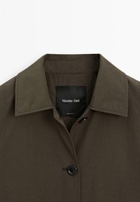 Camicia color khaki con colletto classico, caratterizzata da una chiusura con un solo bottone, realizzata in materiale leggero. L'etichetta riporta "Massimo Dutti."