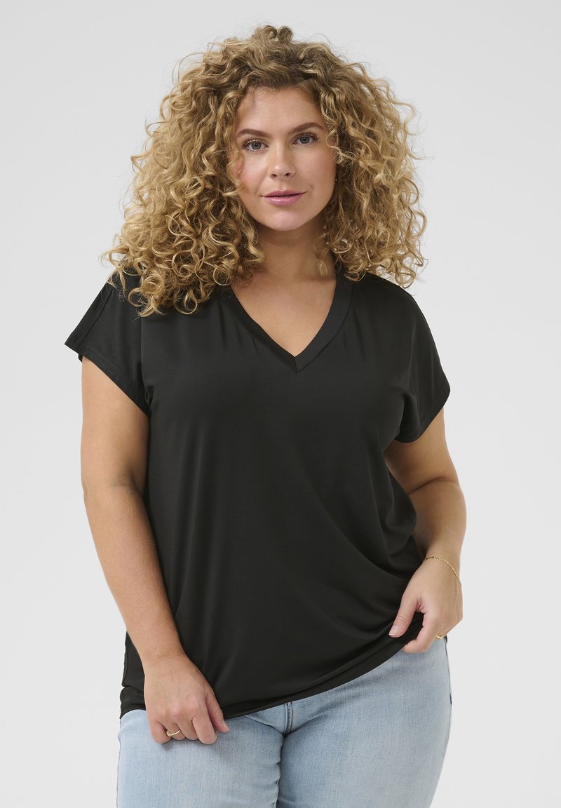 Sort V-hals T-shirt lavet af glat stof, med korte ærmer og en afslappet pasform. Båret med lyseblå jeans.