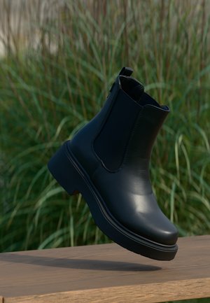 Black leather ankle boots with elastic side panels, rounded toe, and a thick platform sole, positioned on a wooden surface.