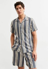 Set di camicia a maniche corte e pantaloni corti in cotone, con strisce verticali blu e beige, una singola tasca sul petto e un colletto con bottoni.
