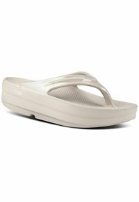 Beige šlepetės su blizgiu, lygiu viršumi, tekstūruotu padu ir palaikančiu platformos padu. Minimalistinis dizainas su atvira pirštų dalimi.