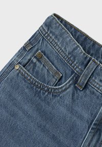 Denim jeans in medium blue, met een klassieke snit, een klein voorvak en gestikte details. De stof heeft een gestructureerde, duurzame uitstraling.