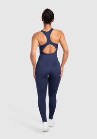 Světlomodrý sportovní kombinéza s designem na zádech a hlubokým výstřihem, vyrobený z elastické tkaniny, která těsně přiléhá.