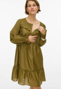 Õlivärvi roheline kleit, valmistatud kerge kangaga, kaunistatud volangidega kaeluse ümber, ees nööbitav ja mitmekihilise äärega. Pikkade, punnitavate varrukatega.