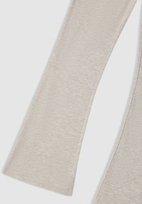 Gambe di pantaloni in tessuto grigio chiaro con cuciture visibili, che mostrano un taglio leggermente svasato su uno sfondo neutro.