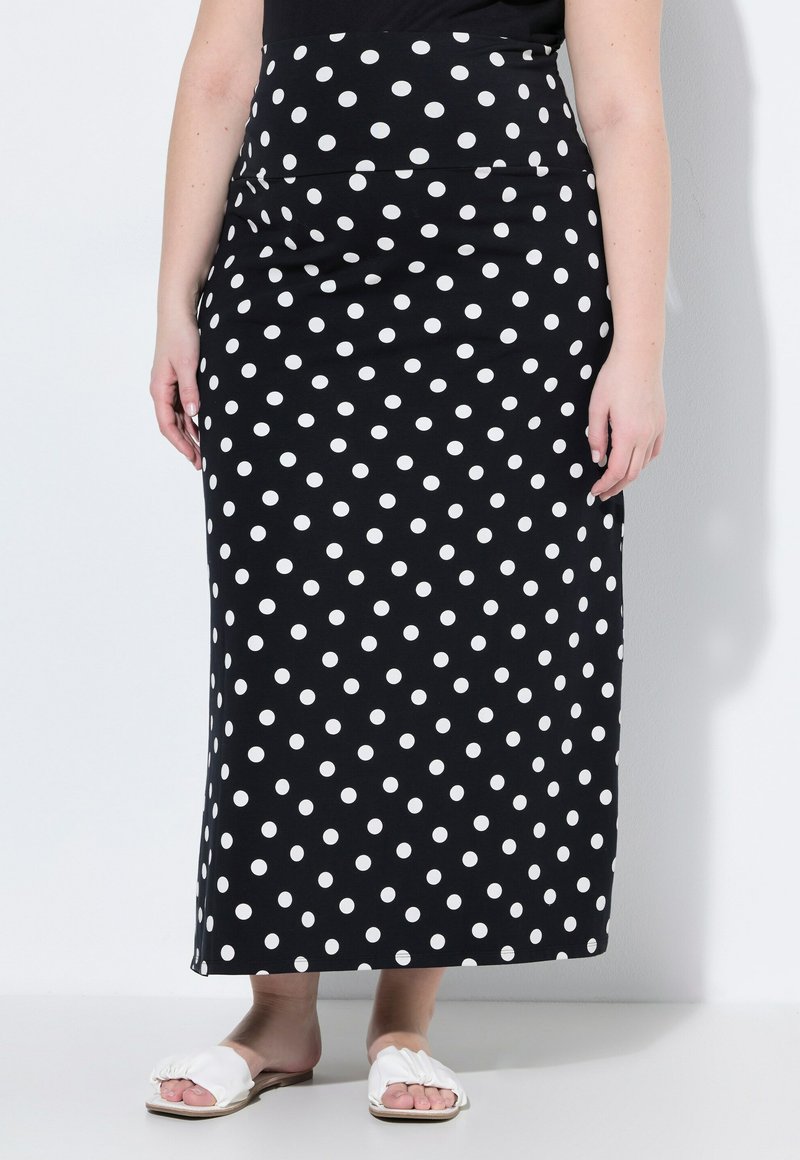Zwarte maxi rok met een aansluitende taille, versierd met witte stippen. Soepele textuur, gecombineerd met witte platte sandalen.