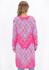 Fuzzy roze en lavendel lange cardigan met diamantpatronen, kleurrijke accenten en textuur op de mouwen. Overdreven lengte en een relaxte pasvorm.