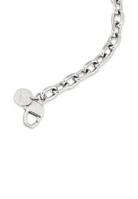 Zilveren armband met grote, ovale schakels en een sluiting. Inclusief een klein rond label met de gravure "Sutoria." Gladde metalen afwerking.