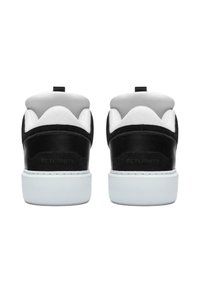 Czarne zamszowe i białe siateczkowe trampki z białą gumową podeszwą, wyposażone w pętlę na pięcie oraz wytłoczone logo po boku.