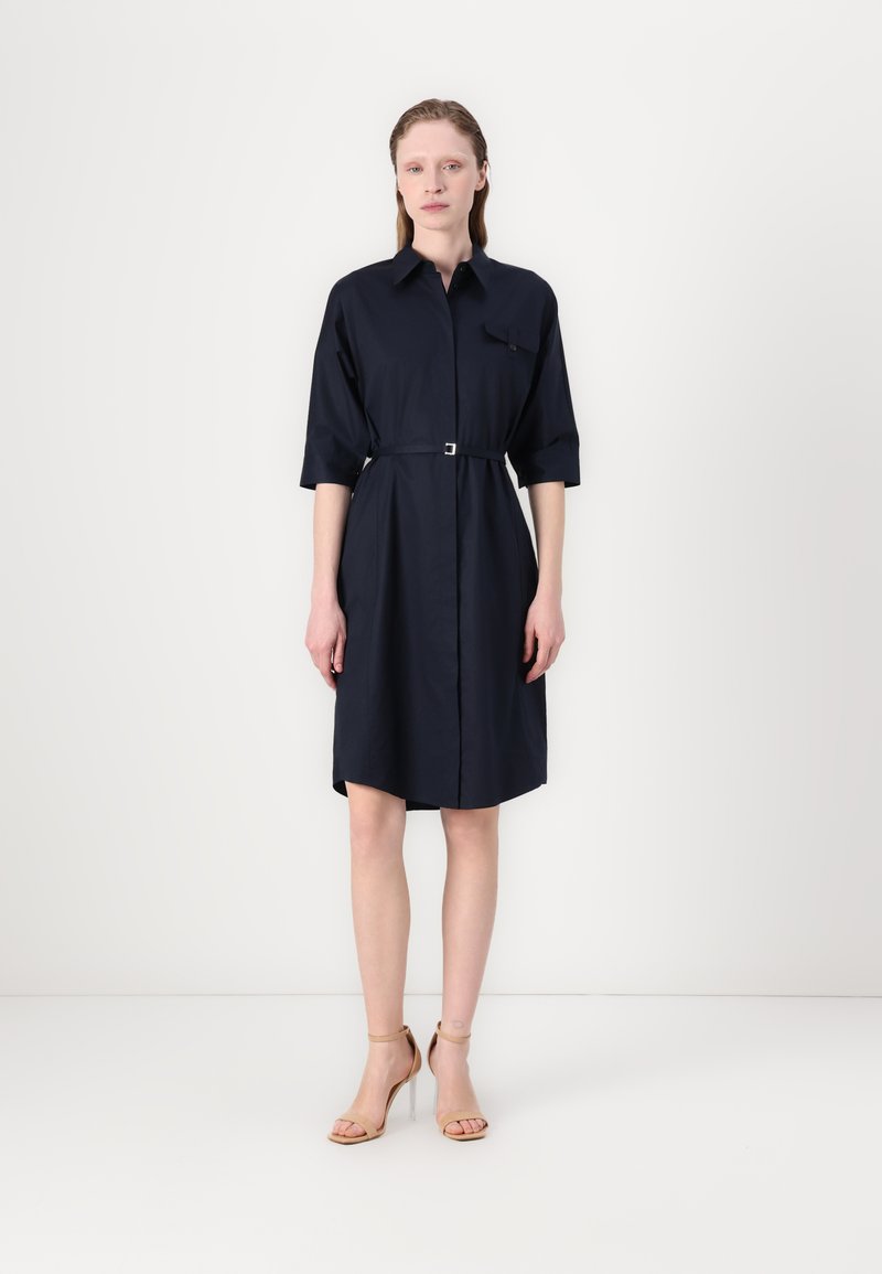 Navy blue shirt dress with a collar, three-quarter sleeves, and a belted waist. Features a button-up front and single chest pocket.