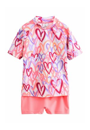 Piges to-delte badetøjssæt med kortærmet top med hjerteprint i pink, lilla og orange, kombineret med ensfarvede koral-pink bade-shorts.