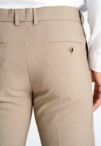 Pantaloni su misura marrone chiaro, tessuto testurizzato, design con fronte piatto, due tasche posteriori con chiusura a bottone, vestibilità su misura.