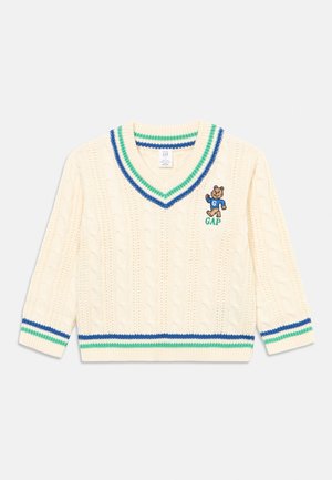 Suéter de punto color crema con cuello en V y rayas azules y verdes en el cuello, los puños y el dobladillo, con un pequeño logotipo de oso y el texto "GAP" en el pecho.