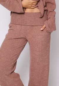 Pantaloni da loungewear leggeri e a coste in un colore rosa tenue, dotati di una fascia in vita ampia e tasche laterali per praticità e comfort.