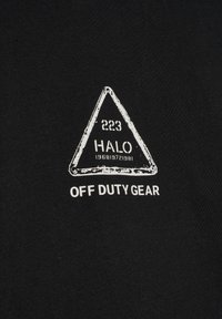 Weißes Dreieck mit dem Text „223 HALO 196819721981“ über „OFF DUTY GEAR“ auf schwarzem Stoffhintergrund.