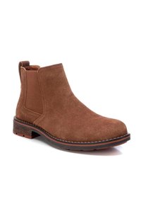 Bota Chelsea de suede marrón con paneles laterales elásticos, puntera redonda y entresuela texturizada. Presenta una ligera franja roja elevada en la suela.