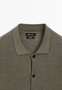 Polo en maille vert olive avec col et deux boutons noirs, étiqueté Massimo Dutti, en 100 % lin.