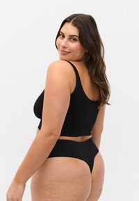 Czarny crop top z szerokimi ramiączkami, w połączeniu z czarnymi majtkami o wysokim stanie. Miękka tkanina, minimalistyczny design i gładka tekstura.