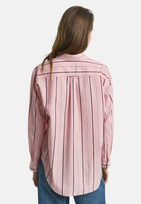 Rosa randig skjorta i tyg med vertikala blå ränder, med knappad krage, långa ärmar och rundad fåll.
