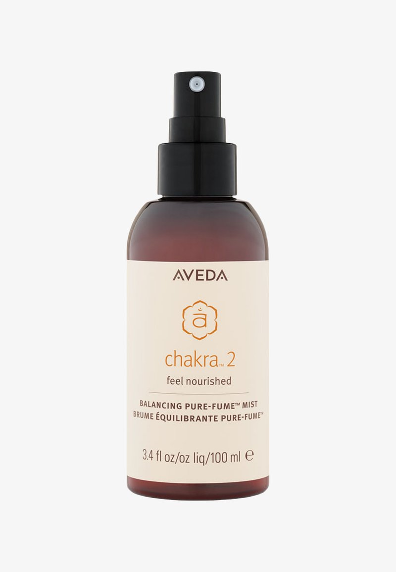 Brązowa szklana butelka z rozpylaczem i czarną pompką, oznaczona "Aveda Chakra 2." Na etykiecie znajdują się napisy "poczuj się odżywiony" oraz "Balancing Pure-Fume Mist."