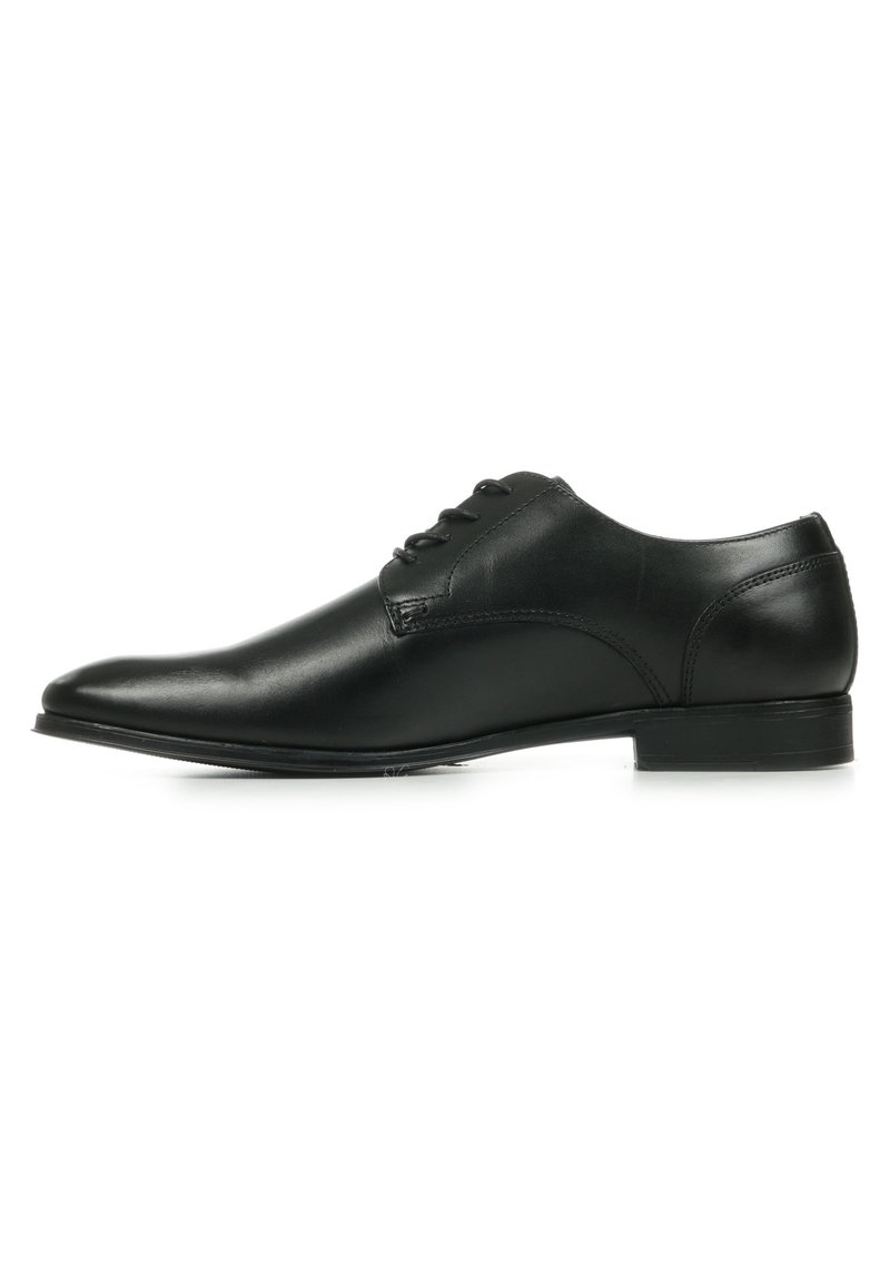 Zwarte leren dresschoenen met een gladde afwerking, ronde neus en lage hak. Voorzien van een vetersysteem met dunne oogjes en minimale stikdetails.