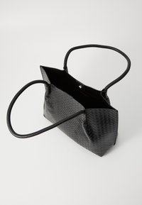 Borsa in pelle intrecciata nera con manici arrotondati, apertura superiore che mostra un ampio interno, su uno sfondo bianco uniforme.