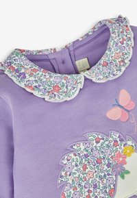 Felpa lilla con colletto a fiori, caratterizzata da un ricamo di farfalla e un design floreale, texture morbida e scollatura rotonda.