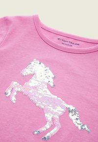 T-shirt in cotone rosa con scollatura rotonda, caratterizzato da un design di unicorno in paillettes bianche e iridescenti sul davanti.