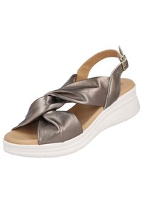 Sandaña de bronce metálico con diseño de tira retorcida, punta abierta y correa ajustable en el tobillo. Acabado texturizado en la parte superior, suela blanca acolchada.