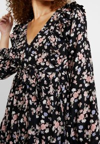 Černé květinové šaty s volánkovým výstřihem, dlouhými rukávy a zúženým pasem. Disponují kombinací růžových, bílých a modrých květin na lehké látce.