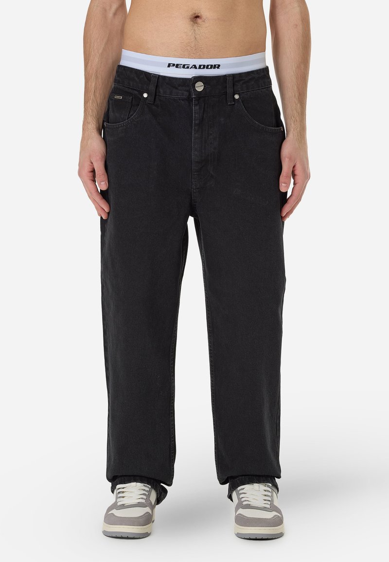 Czarne dżinsy o prostym kroju, z kieszeniami z przodu, z zapięciem na guzik i paskiem z marką PEGADOR. Noszone z neutralnymi trampkami.