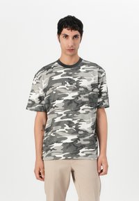 Grå camo t-skjorte med korte ermer, rund hals, og et lite logo-lapp på brystet. Laget av myk bomullsblanding.