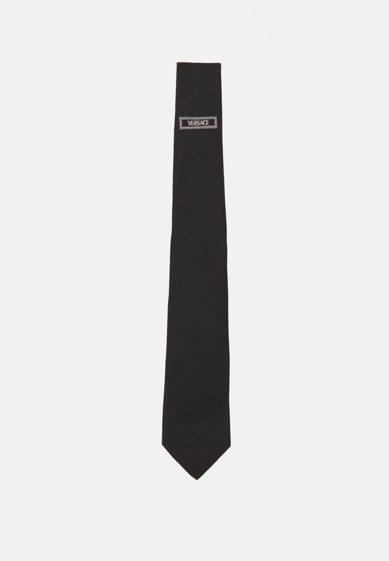 Schleife aus glattem Stoff, mit spitzem Ende und einem kleinen weißen Markenetikett nahe der Oberkante. Minimalistisches Design, ohne Muster.