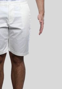 Pantaloni corti di cotone bianchi con risvolti, dotati di chiusura con bottone anteriore e tasche. Il materiale sembra liscio con una leggera lucentezza.