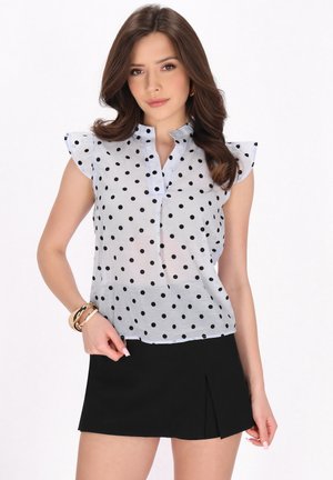 Lichtblauw doorschijnend blouse met zwarte stippen, korte ruches mouwen, staande kraag en knoopsluiting, gecombineerd met een zwarte rok.