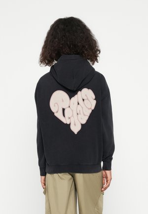 Black hoodie featuring a large, light pink, heart-shaped "Pegar a Vador" graphic on the back. Soft fabric with a relaxed fit and drawstring hood.