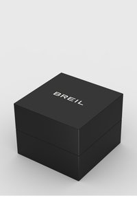 Boîte rectangulaire noire avec une texture lisse, arborant un logo blanc "BREIL" sur le dessus. Design épuré et minimaliste.