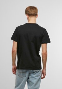 Svart bomull T-skjorte med rund hals, korte ermer og et enkelt design. Bakfra viser den en avslappet passform uten synlige mønstre.